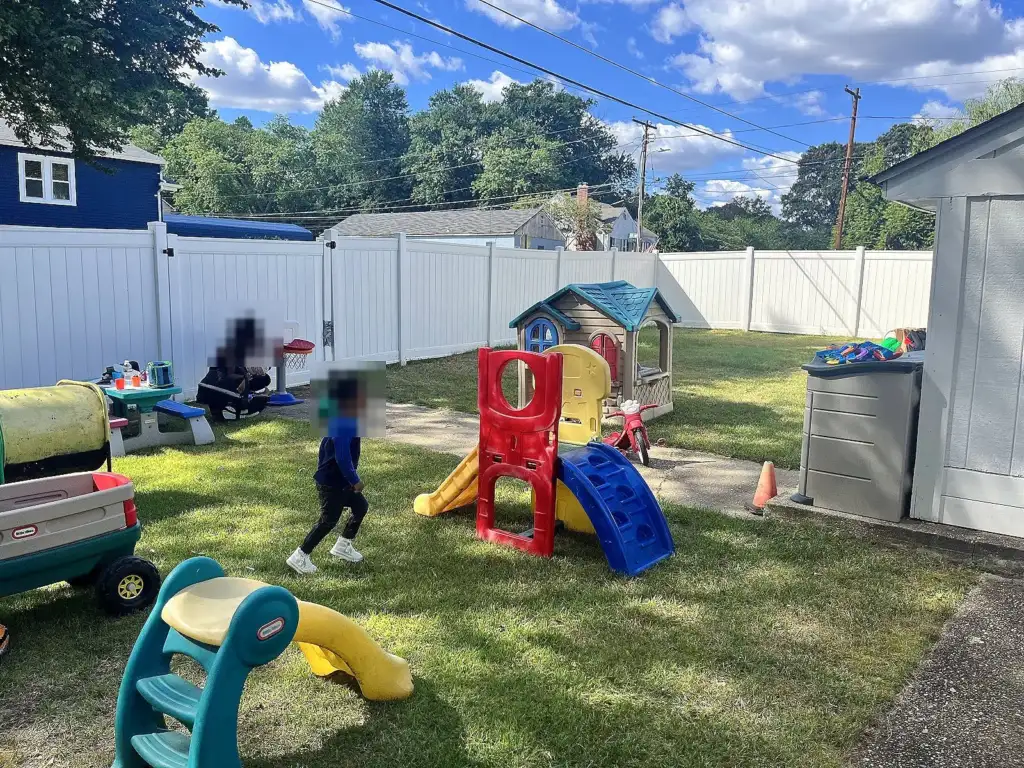The fenced backyard play area with slides and a playhouse