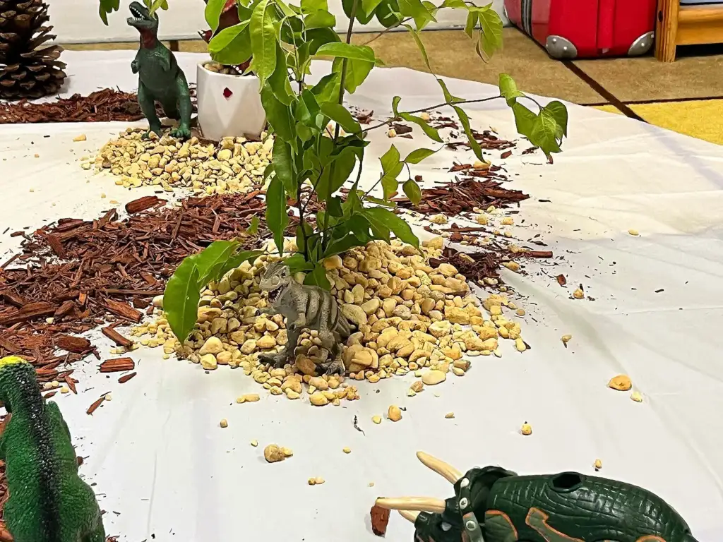 Dinosaur small-world sensory table with stones, bark and plants
