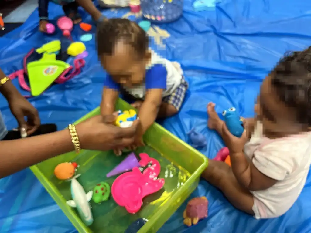 Infants exploring a water and toy sensory bin