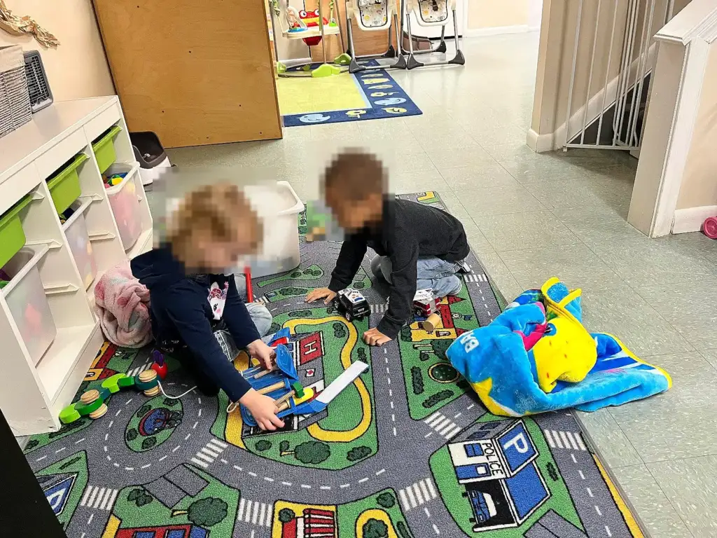 Two toddlers playing on a road-map rug